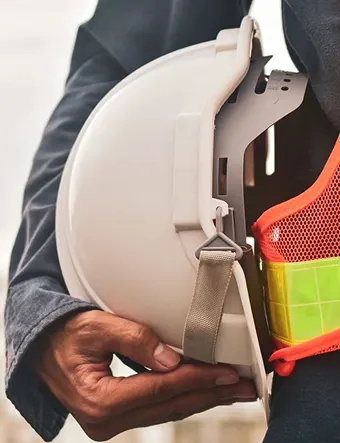 Construction professional holding hard hat and high-visibility vest